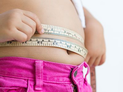 child measuring belly with tape measure