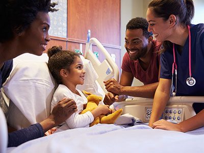 Happy girl in hospital bed surrounded by doctors