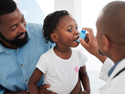 Doctor helping child with asthma inhaler