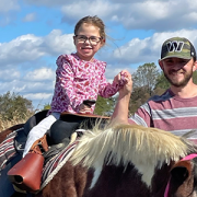 Cayden rides a horse with her father