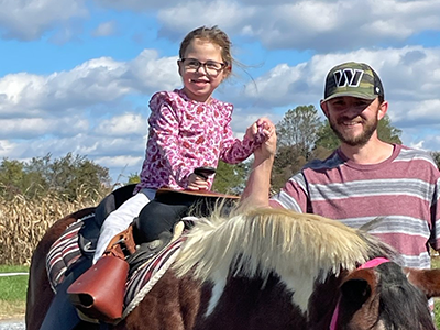 Cayden rides a horse with her father