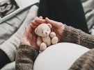 Pregnant teen girl holding small stuffed bear