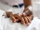 close up of mother holding daughter's hand in hospital