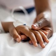 close up of mother holding daughter's hand in hospital