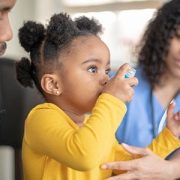 little girl using asthma inhaler