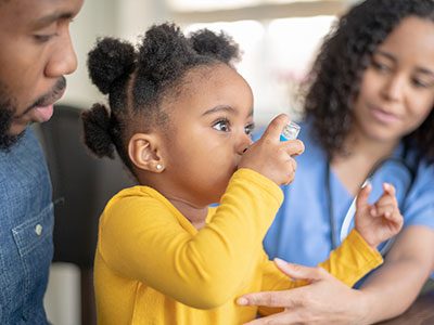 little girl using asthma inhaler