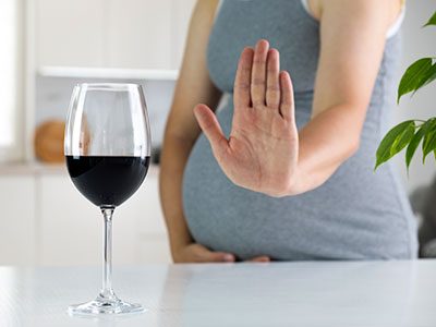 Pregnant woman saying no to a glass of wine.