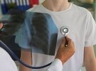 Doctor holding chest x-ray up to boy's chest