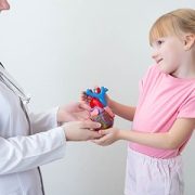 doctor-girl-heart-feature doctor and little girl holding a model of a heart