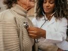 doctor listening to woman's heart with a stethoscope