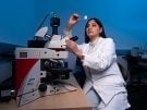 Ashima Gulati, MD, PhD, looking at a slide in the lab