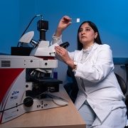 Ashima Gulati, MD, PhD, looking at a slide in the lab